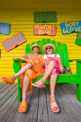 Two-colorfully-dressed-women-share-a-laugh-outside-thier-shop-near-Pigeon-Key-Florida,-USA